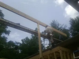 Carpenter setting a ridge beam over a new addition frame — Ice Dam Removal by Roofing Brothers in Belen