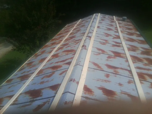 Rusted metal roof panels with new wood purlins before replacement — Storm Damage Roof Repair in Belen by Roofing Brothers