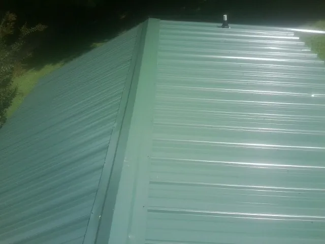 New green metal panels meeting at the ridge of a roof — Flat Roof Repair work by our crew in Belen