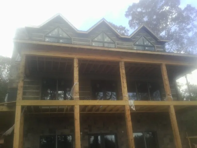 Dormers and porch framing on a large log home under construction — Roof Coating work by our crew in Belen