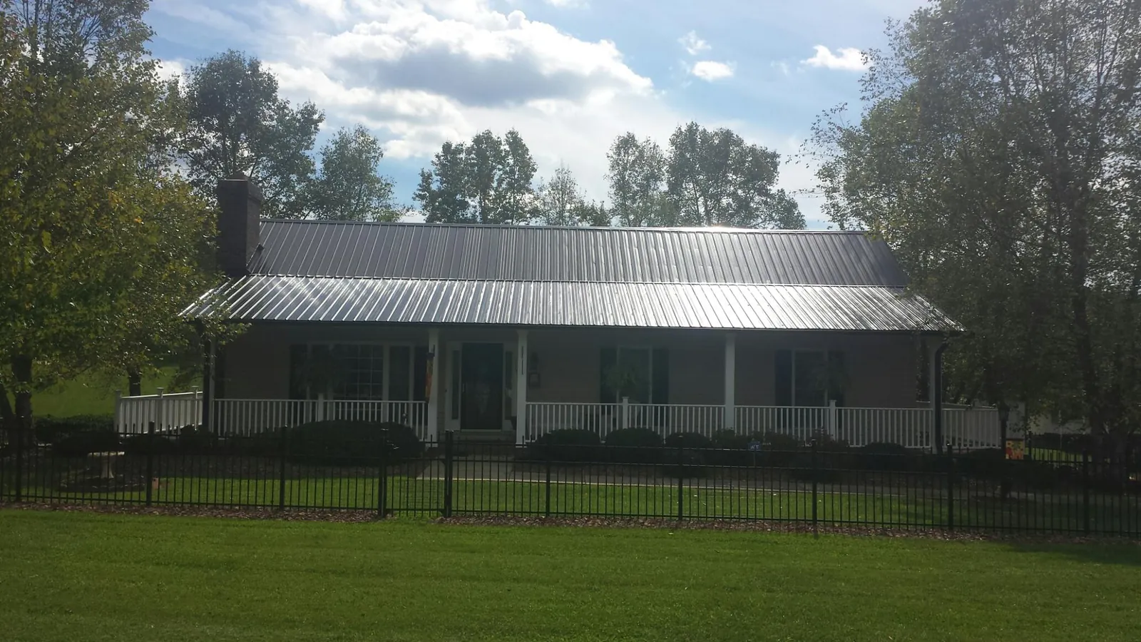 Gray metal roof on a brick ranch with a full width front porch — Gutter Guard Installation work by our crew in Belen