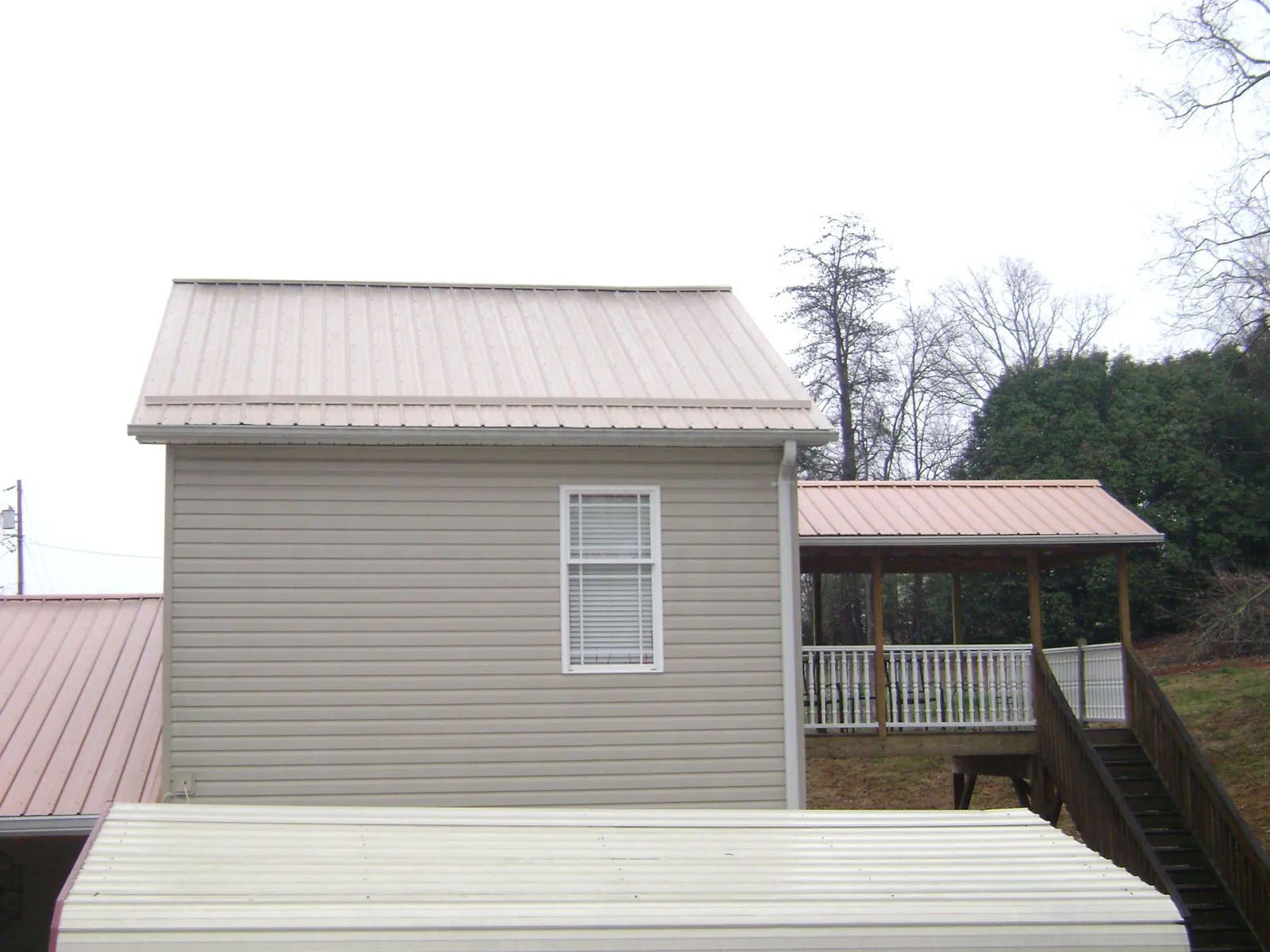 Tan metal roofs on a two story addition and attached porch, from a Roof Replacement job in Belen