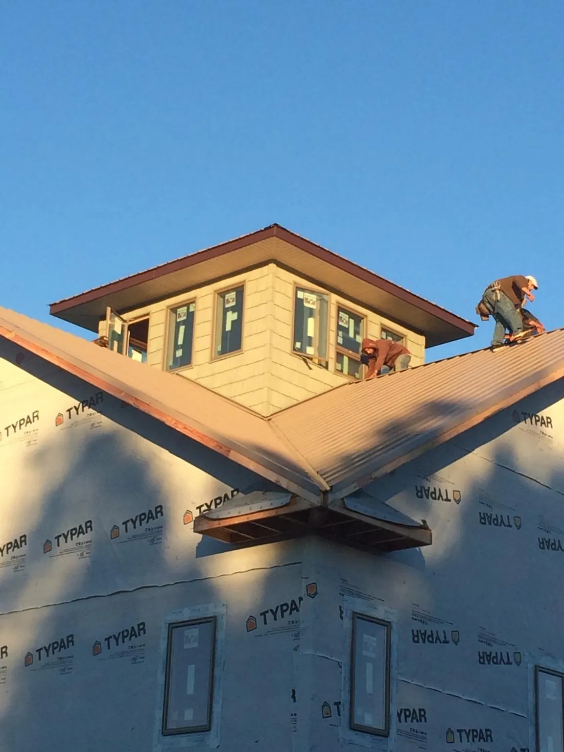 Roofers working around a rooftop cupola on a new metal roof at sunset — Roof Waterproofing in Belen by Roofing Brothers